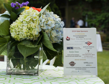 a bouquet of hydrangeas sitting on a table beside a plaque listing 2019 Gala Sponsors